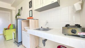 Una cocina compacta con un lavamanos integrado, un refrigerador pequeño y una estufa a gas.
