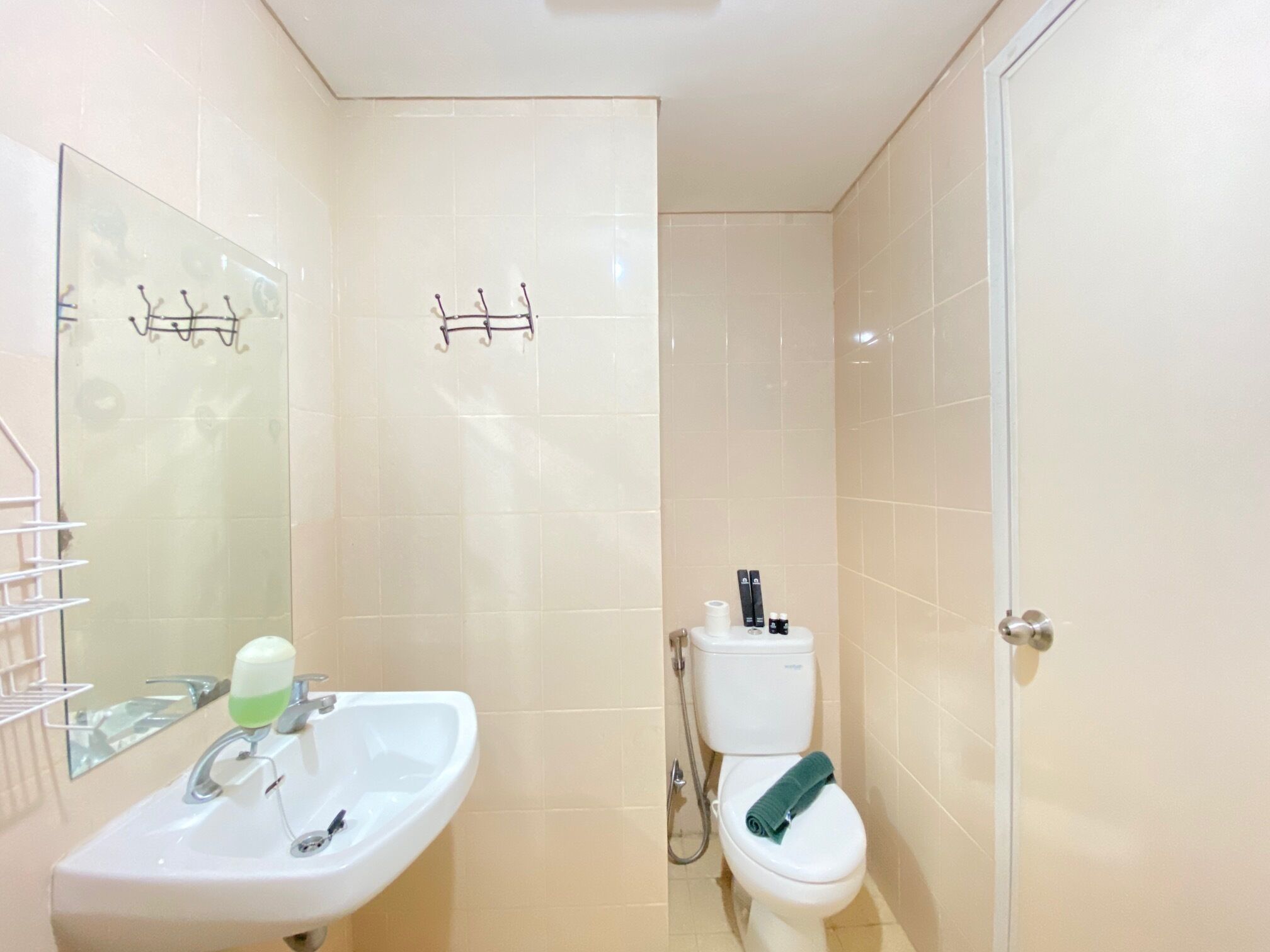 A bathroom with a sink, mirror, toilet, and towel rack.