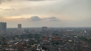 Eine Stadtansicht mit einer Mischung aus Hochhäusern und kleineren Gebäuden, verschiedenen Architekturstilen und einem bewölkten Himmel.