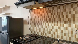 Eine Küche mit einem schwarzen Kühlschrank, einem Gasherd und einer gefliesten Spritzwand.