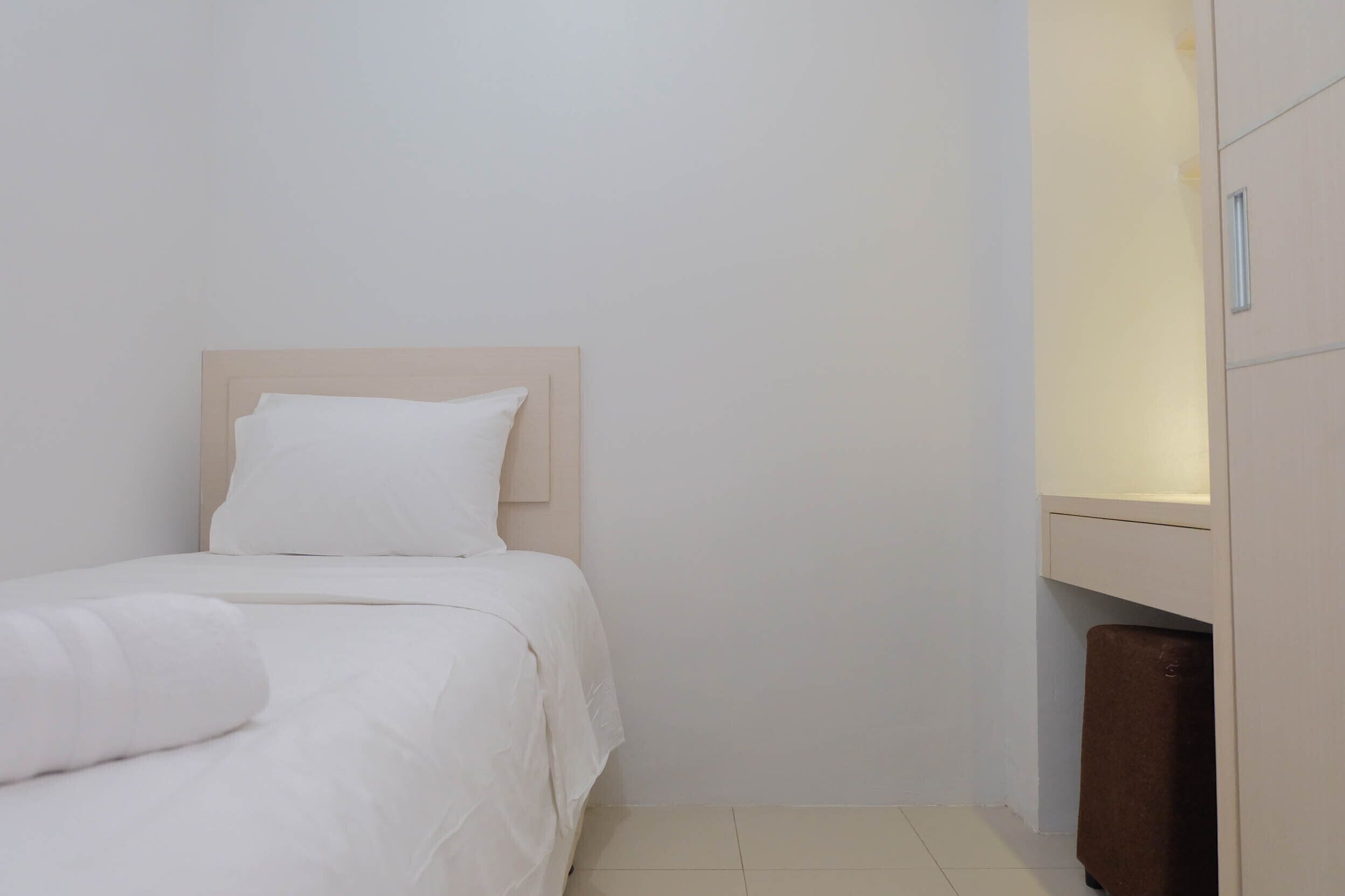A small, neatly made bed with a wooden headboard in a minimalistic room.