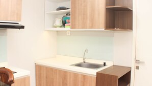 Une cuisine de taille réduite, équipée d’un évier, de meubles de rangement en bois et d’un plan de travail.