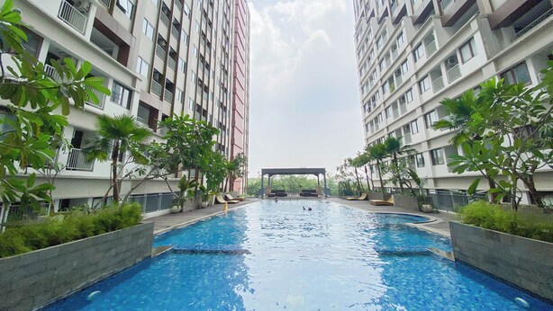 A swimming pool surrounded by high-rise residential buildings with balconies. - Best Choice and Comfy Studio Apartment LRT City Bekasi (Bekasi)