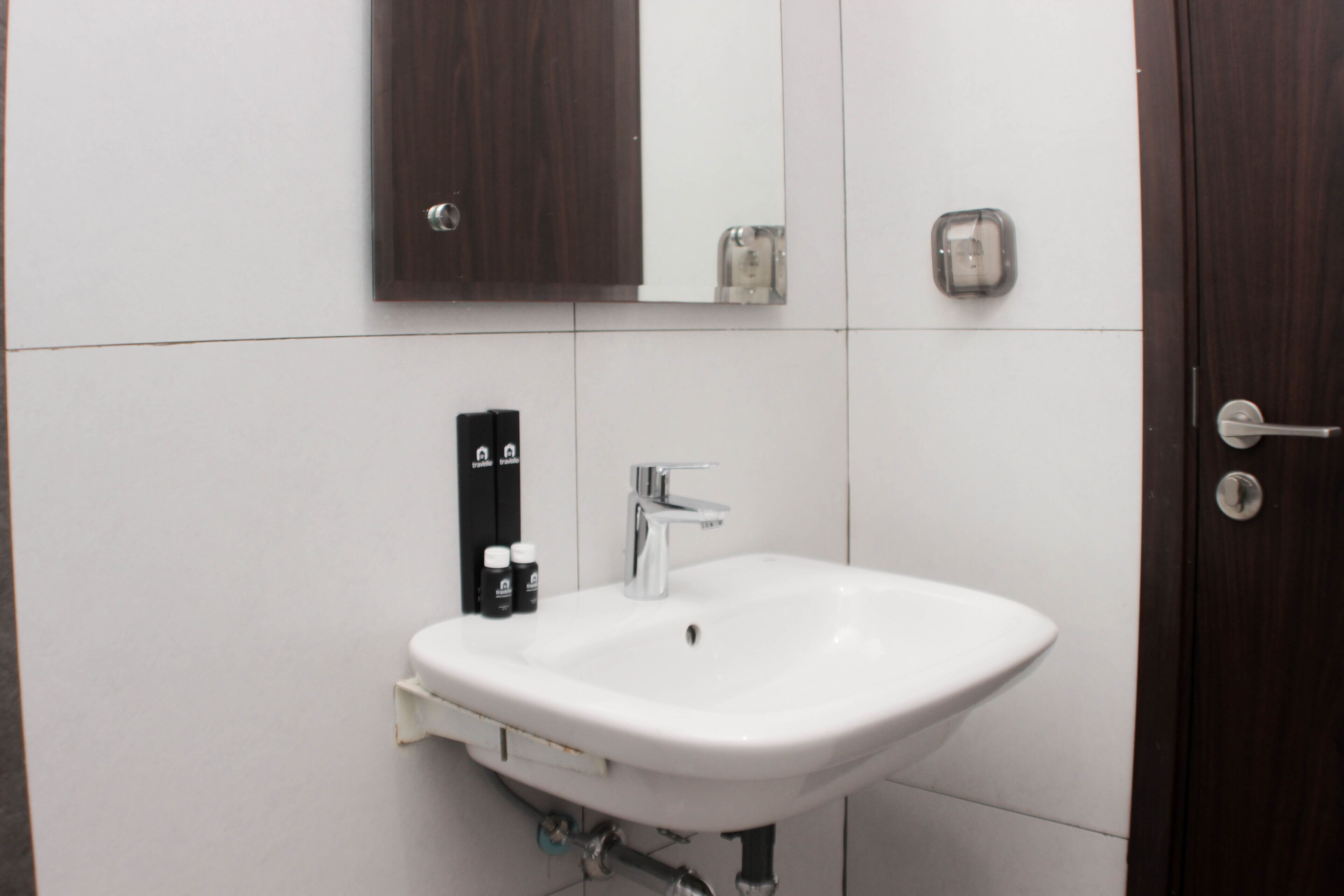 A bathroom with a white sink, a mirror, and a soap dispenser.