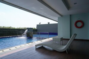 An indoor swimming pool with a lounge chair and a red lifebuoy on the wall. - Cozy Living Studio Apartment At Belmont Residence Near Puri (Jakarta)