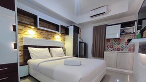 Una habitación de hotel moderna con una cama grande, un armario empotrado, una kitchenette y una decoración llamativa.