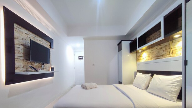 Una habitación de hotel moderna con cama, TV empotrada y una pared decorativa de piedra.