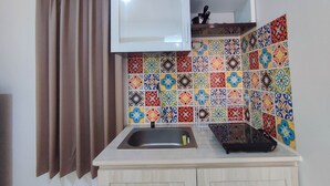 Una cocina con un lavamanos, un armario y un salpicadero de azulejos.