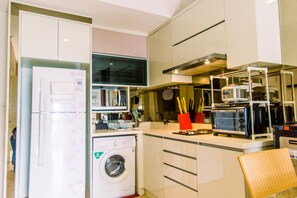 Uma cozinha compacta com geladeira, máquina de lavar e cafeteira.