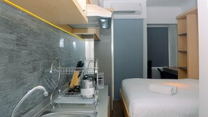 A compact hotel room with a kitchenette, a bed, and a shower area. - Fully Furnished Studio At Springlake Summarecon Apartment (Bekasi)