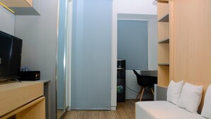 A compact room with a TV, a desk, a chair, a sofa, and a wardrobe. - Fully Furnished Studio At Springlake Summarecon Apartment (Bekasi)