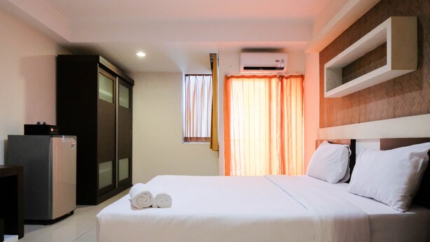 Ein Hotelzimmer mit Bett, Schreibtisch, Kühlschrank und Klimaanlage.