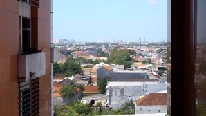 Blick auf eine Stadtlandschaft von einem Hochhaus aus, mit einer Mischung aus Wohn- und Geschäftshäusern, und einem klaren Himmel.