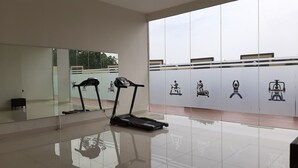 A gym with two treadmills, a mirrored wall, and exercise icons on the wall. - Cozy Stay Studio Apartment At Easton Park (South Tangerang)