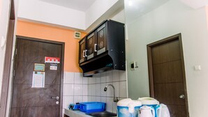 A compact kitchen with a sink, cabinets, and a countertop with a kettle and a blue container. - Cozy Stay Studio Apartment At Easton Park (South Tangerang)