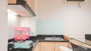 A compact kitchen with a sink, countertop, and wooden cabinets. - Comfort Living 1Br At The Boulevard Apartment (Jakarta)