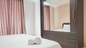 A hotel room with a large bed, a wardrobe, and a mirror. - Comfort Living 1Br At The Boulevard Apartment (Jakarta)