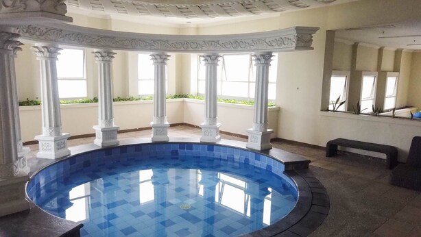 A circular indoor pool with white columns and a tiled floor. - Comfort Living 1Br At The Boulevard Apartment (Jakarta)