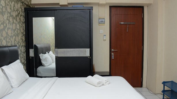 A hotel room with a bed, a chair, a wardrobe, and a door. - Minimalist Studio Room At Kebagusan City Apartment (Jakarta)