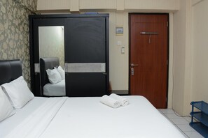 Une chambre d’hôtel avec un lit, une chaise, une armoire et une porte.