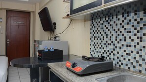 A kitchen with a microwave, a gas stove, and a tiled backsplash. - Minimalist Studio Room At Kebagusan City Apartment (Jakarta)