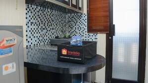 A kitchen area with a black countertop, a sink, and a tiled backsplash. There is a black bag labeled 'Travelio' on the counter. - Minimalist Studio Room At Kebagusan City Apartment (Jakarta)