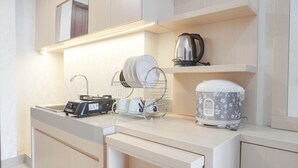 A modern kitchen with a countertop, a kettle, a coffee maker, and a dish rack. - Comfort And Warm 2Br At Parkland Avenue Apartment (South Tangerang)