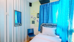 A bedroom with a bed, a chair, and a wall with framed pictures. - Nice Comfort 2Br At Cinere Bellevue Suites Apartment (Depok)