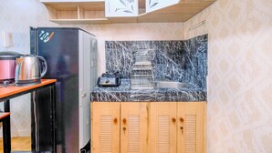 A compact kitchen with a black refrigerator, a coffee maker, and a microwave on a wooden table. - Nice Comfort 2Br At Cinere Bellevue Suites Apartment (Depok)