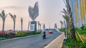 A road with a central business district sign, palm trees, and a heart-shaped structure. - Fancy And Nice Studio @ Springlake Summarecon Bekasi Apartment (Bekasi)