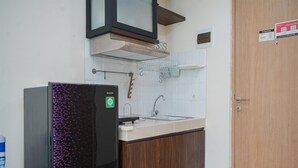 Una cocina con refrigerador, lavamanos y armarios de madera.