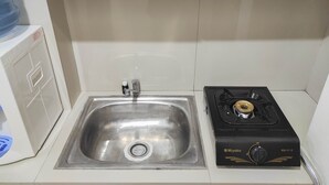 Une cuisine équipée d’un évier en acier inoxydable, d’une cuisinière à gaz et de meubles blancs.