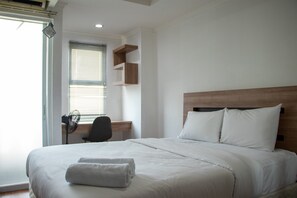 Relax in a cozy space with a neatly made bed, wooden headboard, and desk area.