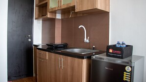 A kitchen with wooden cabinets, a stainless steel sink, and a refrigerator with a water dispenser. - Nice And Comfort Studio Apartment At Belmont Residence Puri (Jakarta)