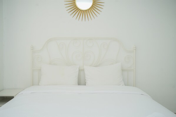 A white bed with a decorative headboard and two pillows. - Strategic And Homey 2Br At Puri Garden Apartment Near Mall (Jakarta)