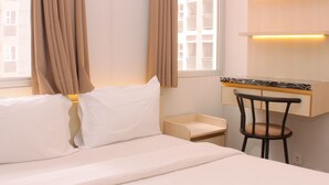 Quarto de hotel com uma cama, uma escrivaninha e uma cadeira.