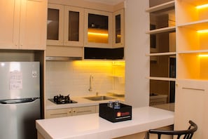 Een keuken met witte kastjes, een roestvrijstalen koelkast, een spoelbak en een aanrecht met een zwart kastje met de tekst 'travelio'.