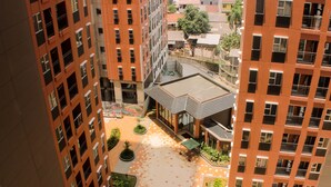 Um edifício alto com várias varandas e um pátio com plantas em vasos.