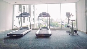 A fitness room with treadmills, a stationary bike, and a rowing machine. - 1Br Apartment With Cozy Design At Royal Olive Residence (Jakarta)