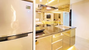 A modern kitchen with a stainless steel refrigerator, a built-in microwave, and a double sink. - Cozy Studio Room At Tamansari La Grande Apartment (Bandung)