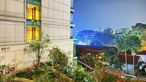 A modern building with a balcony and a view of a cityscape at dusk. - Cozy Studio Room At Tamansari La Grande Apartment (Bandung)