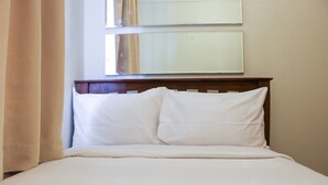 A neatly made bed with white linens and a wooden headboard, positioned against a wall with two large mirrors. - Nice And Elegant 2Br At Grand Palace Kemayoran Apartment (Jakarta)