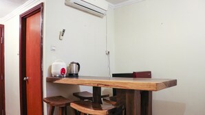 A small dining area with a wooden table and stools, a coffee maker, and a red kettle. - Nice And Elegant 2Br At Grand Palace Kemayoran Apartment (Jakarta)