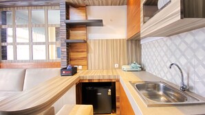 A compact kitchen with a built-in refrigerator, a sink, and a compact stove. - Homey Designed And Cozy 2Br At Mekarwangi Square Cibaduyut Apartment (Bandung)