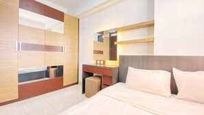 A modern hotel room with a large bed, a desk with a chair, a wardrobe, and a mirror. - Homey Designed And Cozy 2Br At Mekarwangi Square Cibaduyut Apartment (Bandung)