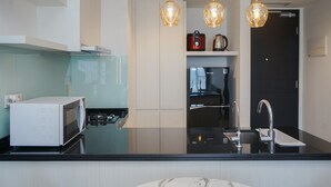 Eine moderne Küche mit Mikrowelle, Herd, Spüle und Deckenleuchten.