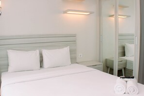 Una camera d'albergo con un letto, un comodino, uno specchio e un set di asciugamani.