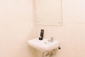 Un bagno con un lavandino bianco, uno specchio e un erogatore di sapone.