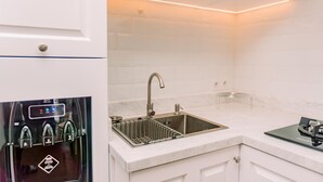 A modern kitchen with a built-in dishwasher, a stainless steel sink, and a marble countertop. - Fancy 2Br Apartment At M-Town Residence Near Summarecon Mall (Gading Serpong)