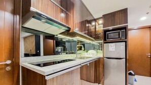 A modern kitchen with a built-in microwave, stainless steel refrigerator, and a sleek countertop. - Great Deal And Cozy 2Br At M-Town Signature Apartment (Gading Serpong)